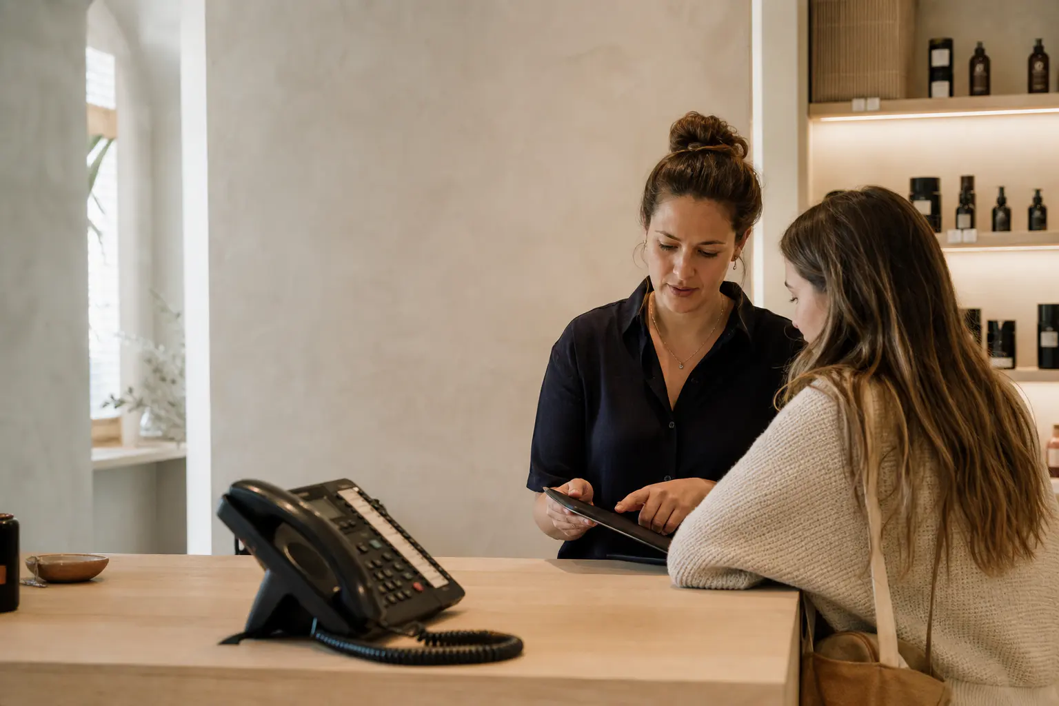 A professional looks after a customer while a call comes in at reception